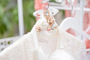 Close-up of an ornate white dress hanger decorated with peach flowers and pearls.