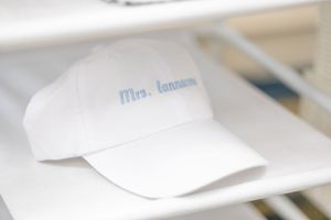 White baseball cap with 'Mrs.' text embroidered in light blue.