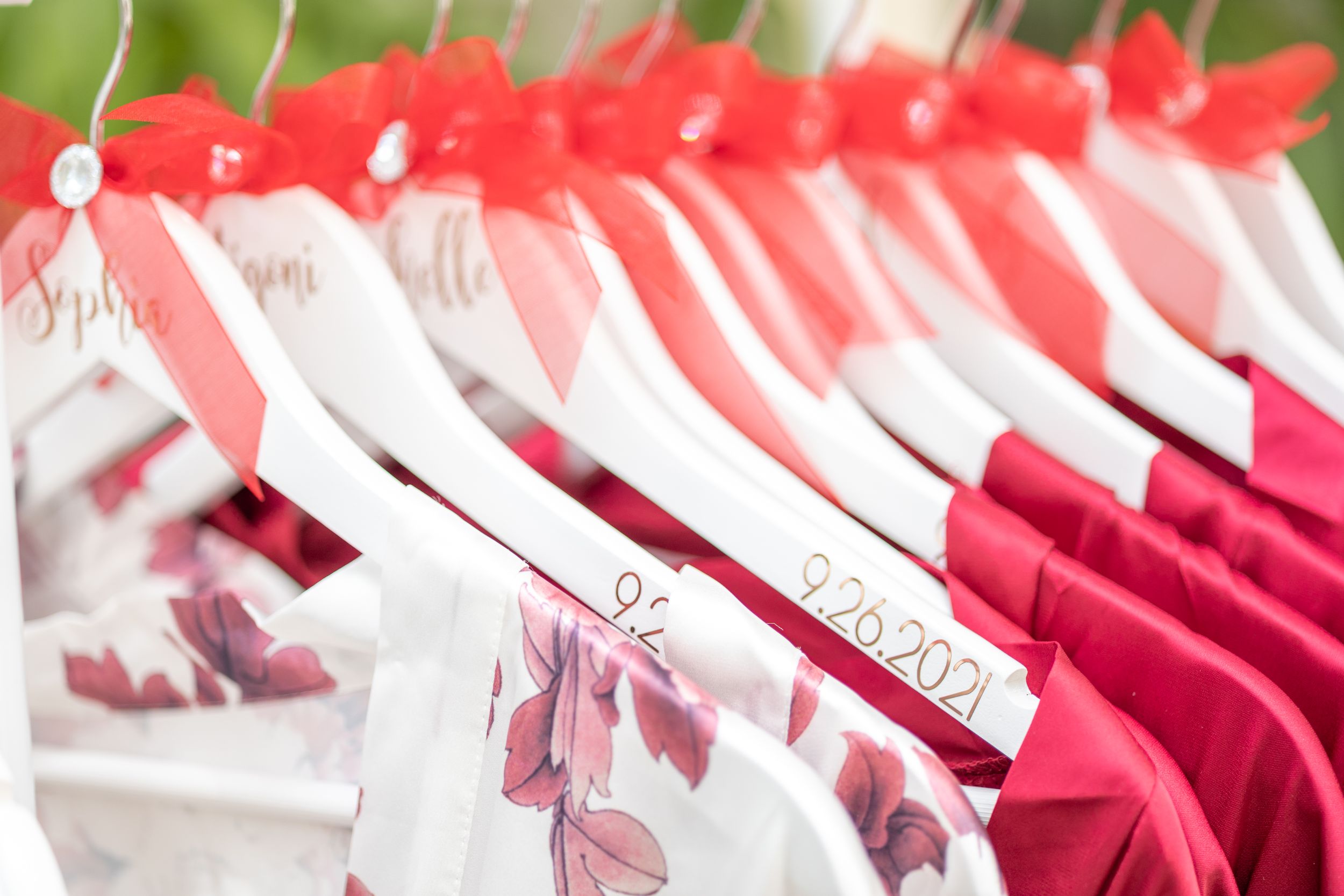 Pink and white customized bridal party robes arranged on hangers with decorative ribbons.