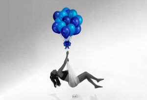 Artistic black and white photo of floating figure with blue balloons.