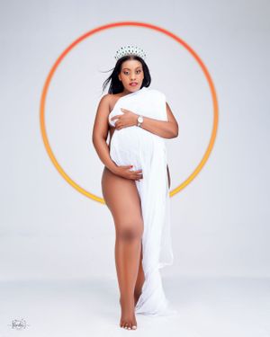 Elegant maternity portrait with white fabric and orange circular backdrop.