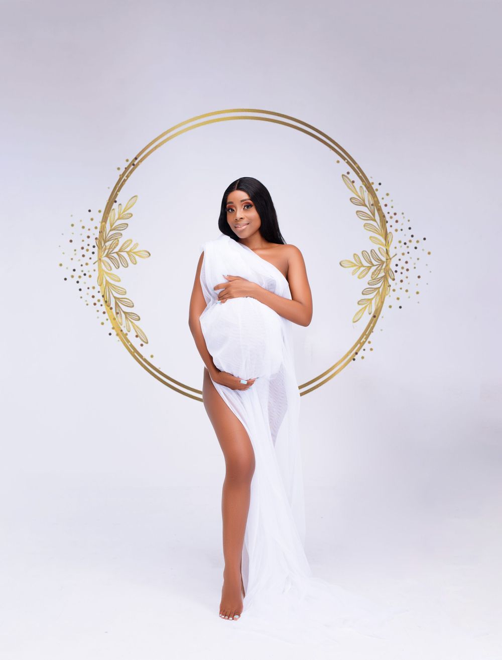Ethereal maternity portrait with white fabric and golden circular frame decoration.