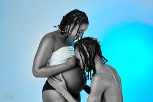 Intimate black and white maternity photo with tender moment between two people.