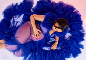 Dramatic maternity portrait with flowing royal blue tulle dress creating a circular pattern around the subject.