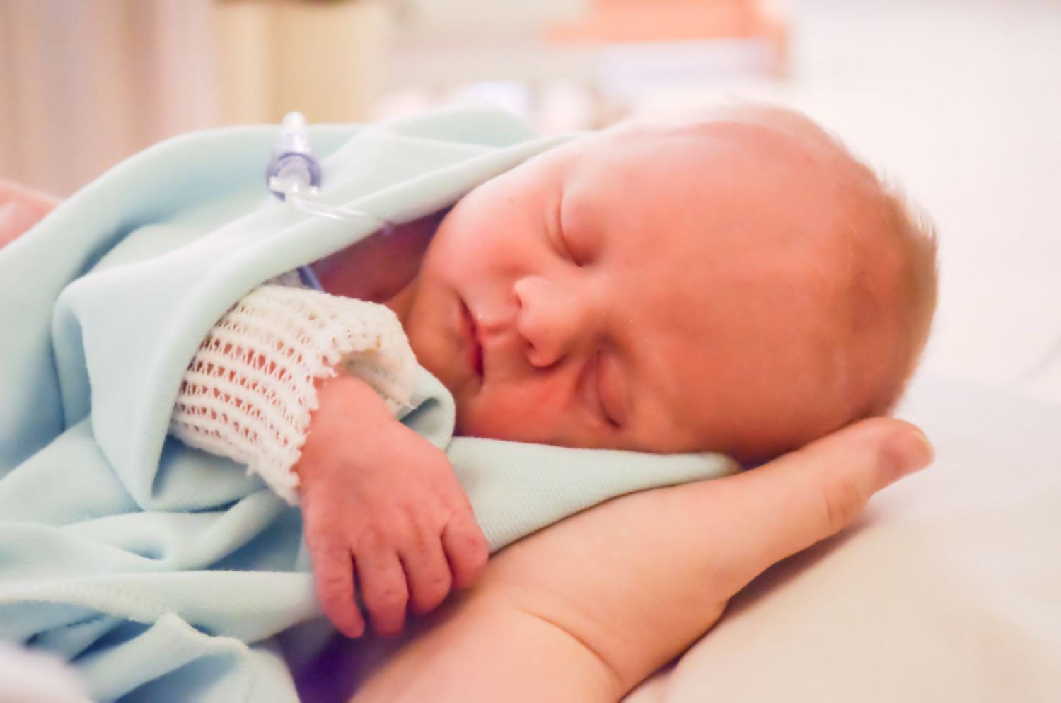 Peaceful sleeping newborn baby wrapped in soft blue blanket.