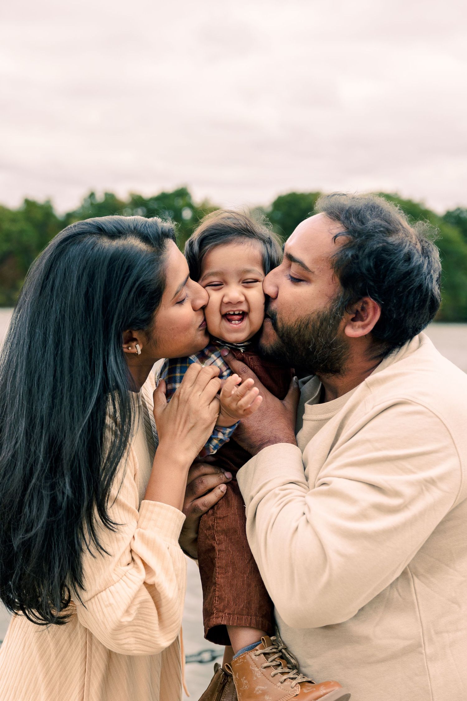 Mother and Father kissing their son outdoors in Michigan