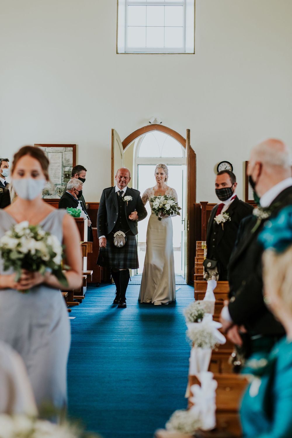 Traditional Scottish wedding ceremony in a church with blue carpeting and white walls.