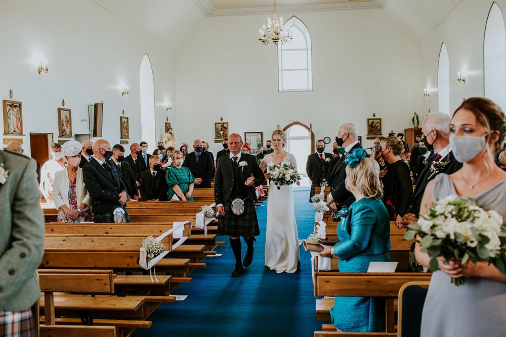 Wedding guests sitting in wooden pews during a traditional Scottish church ceremony.