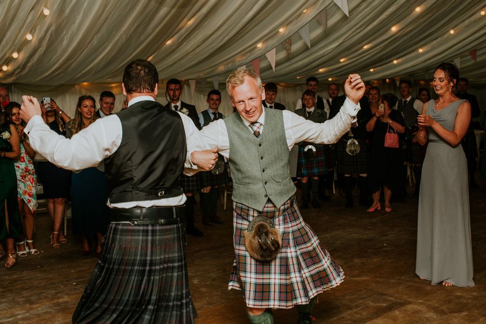 Traditional Scottish dancing with men in kilts at wedding reception.
