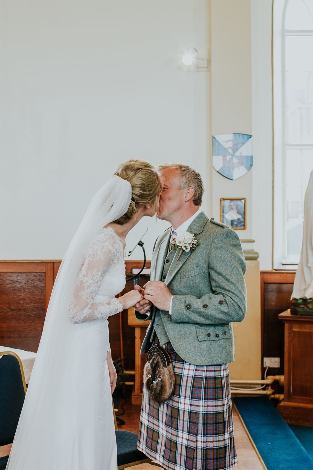 Intimate moment during Scottish wedding ceremony with traditional highland dress.