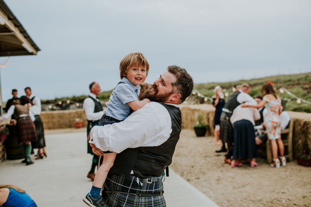 Traditional Scottish wedding celebration outdoors with kilts and scenic countryside views.