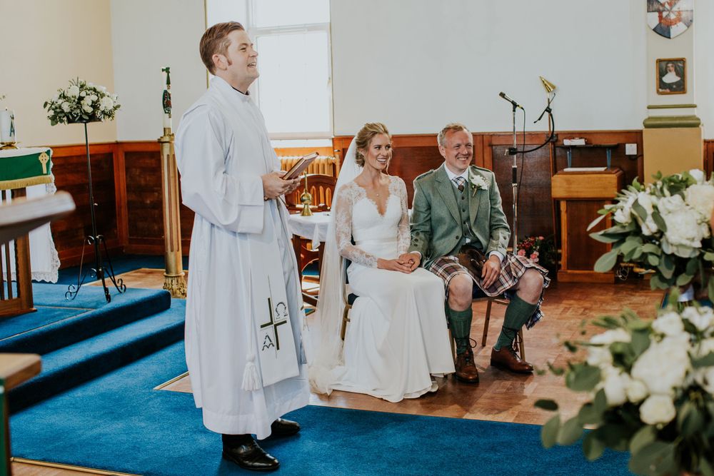 Church wedding ceremony with clergy member and traditional Scottish attire.