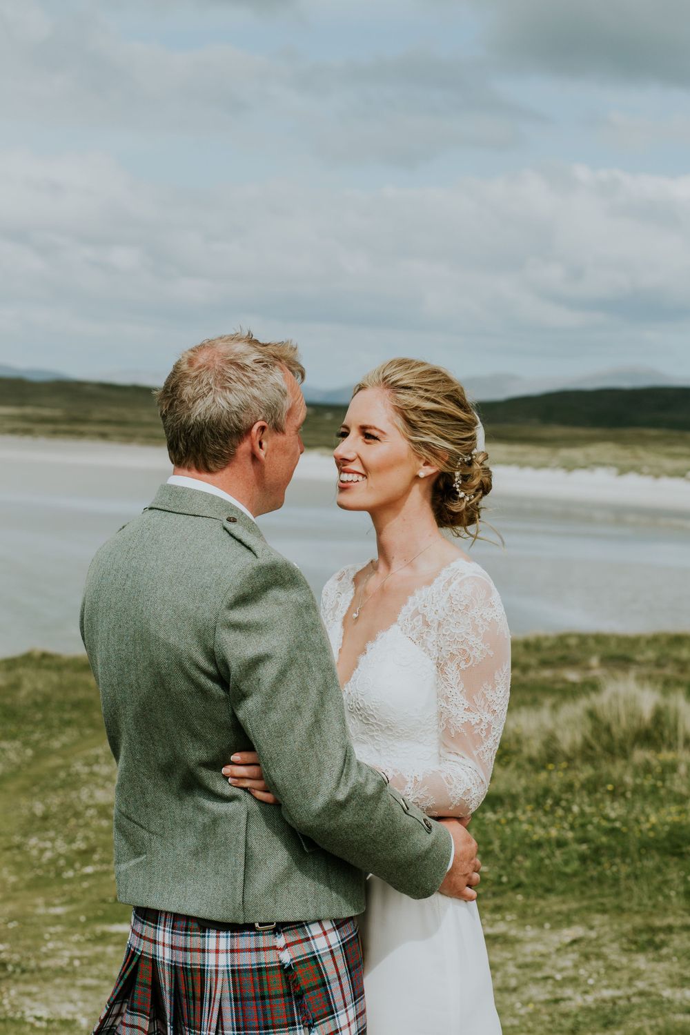 A tender moment between newlyweds with Scottish highlands and ocean in background.