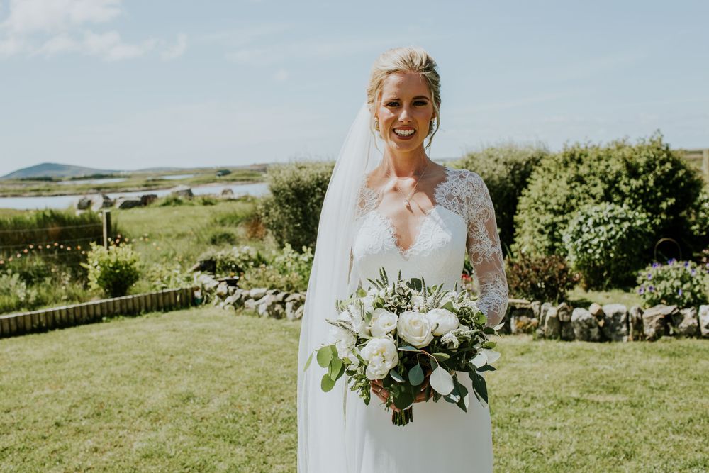 Scenic coastal wedding portrait with white floral bouquet.