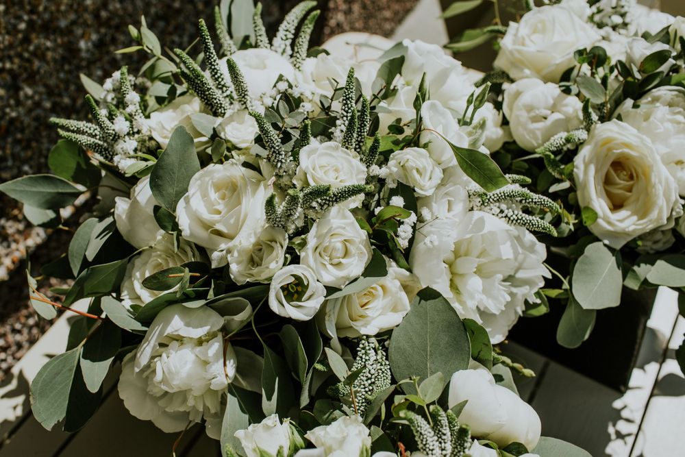 Lush white rose and eucalyptus wedding flower arrangement in natural light.