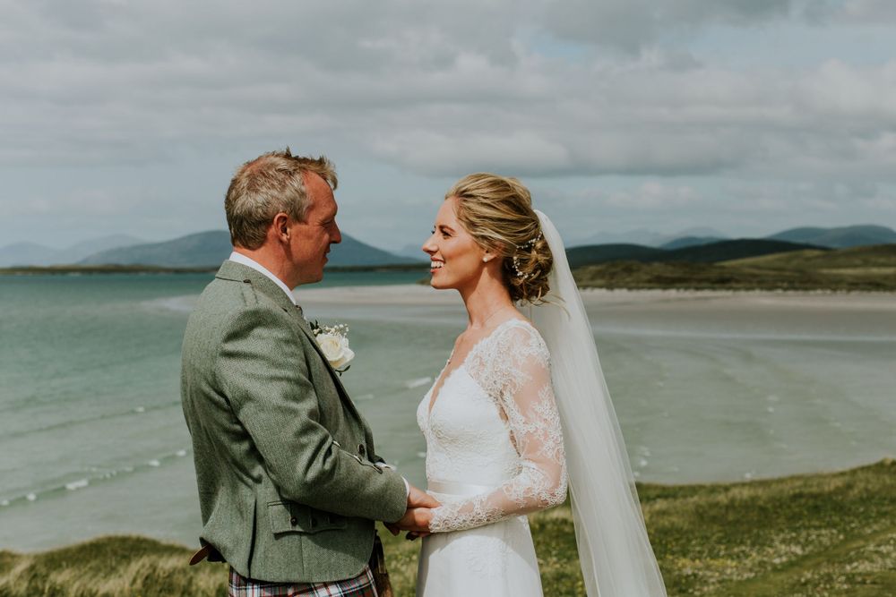 A Scottish wedding couple shares an intimate moment on a cliff overlooking the ocean.