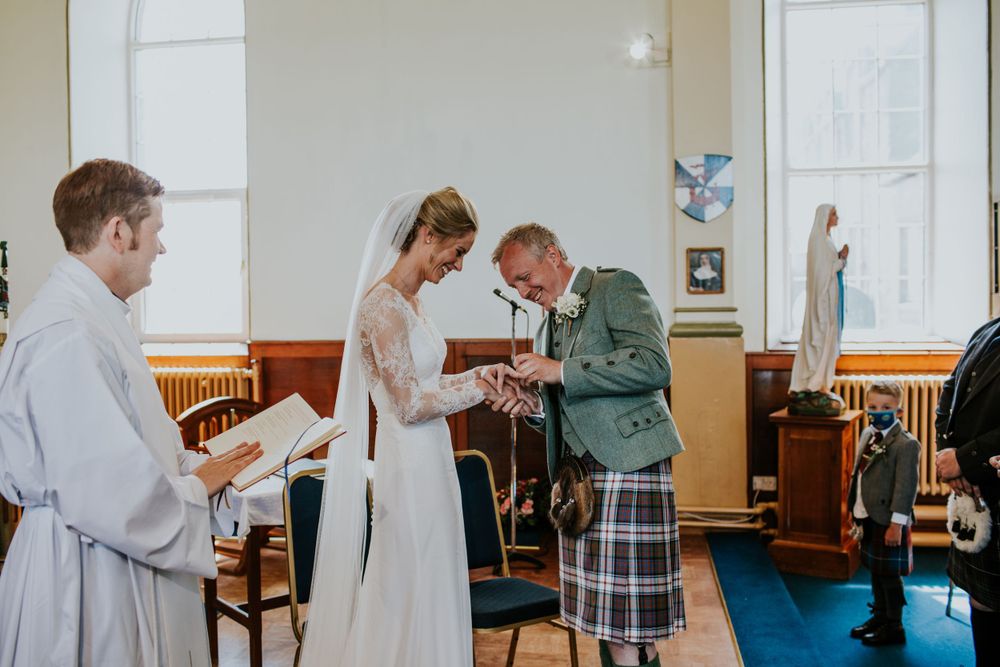 Exchange of rings during Scottish wedding ceremony with minister present.