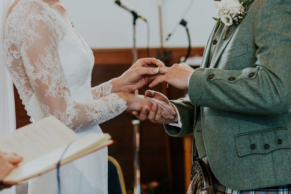 Detailed shot of wedding ring exchange between couple during traditional ceremony.