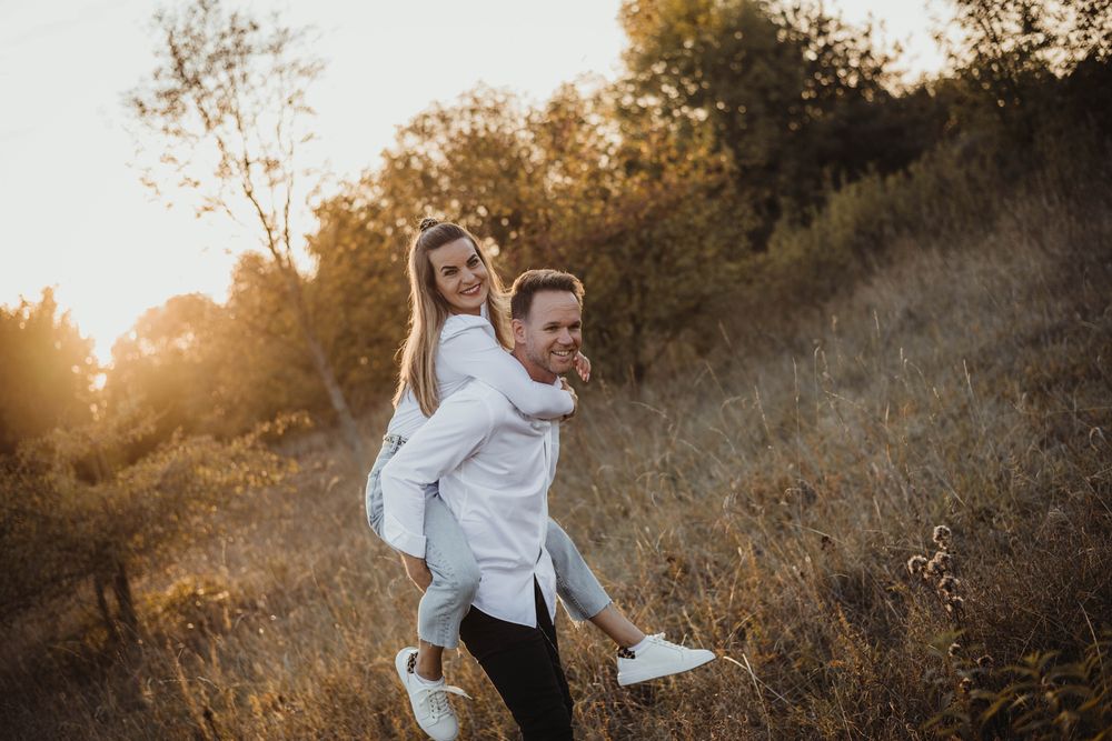 Playful autumn engagement photo session in a rustic field at sunset.