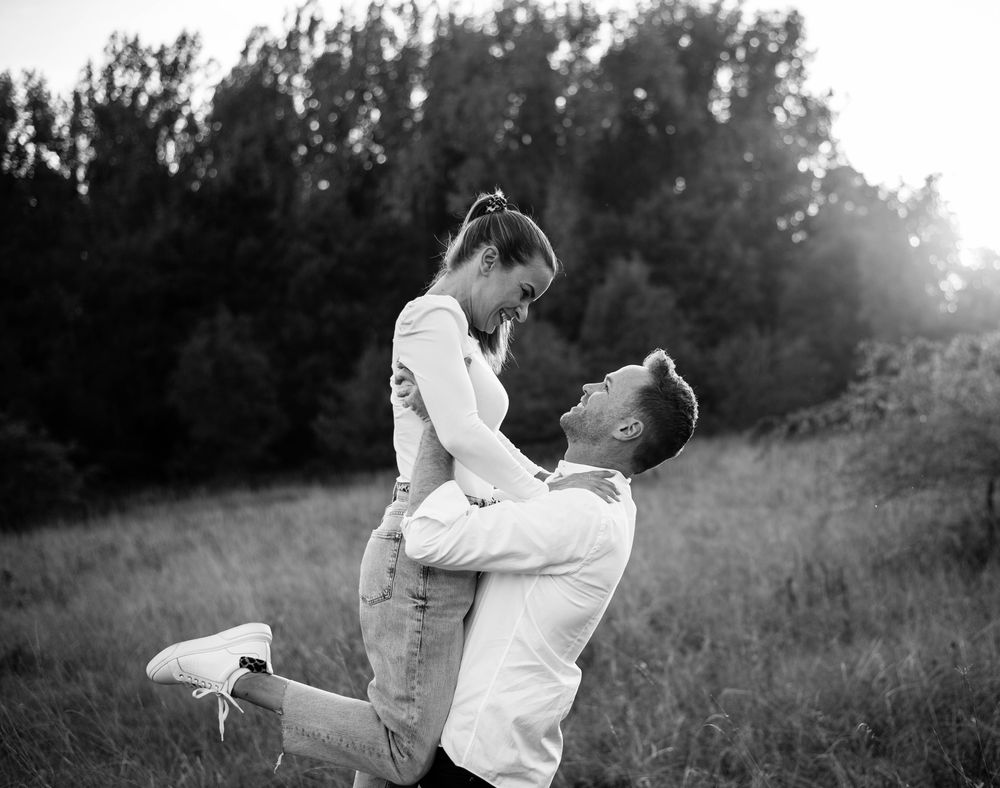 Black and white romantic portrait in a meadow with dramatic lighting.