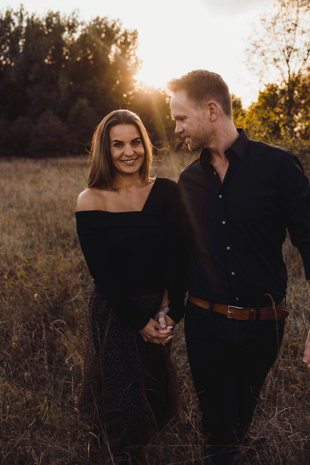 Intimate golden hour portrait in a field with dramatic sunlight and natural backdrop.