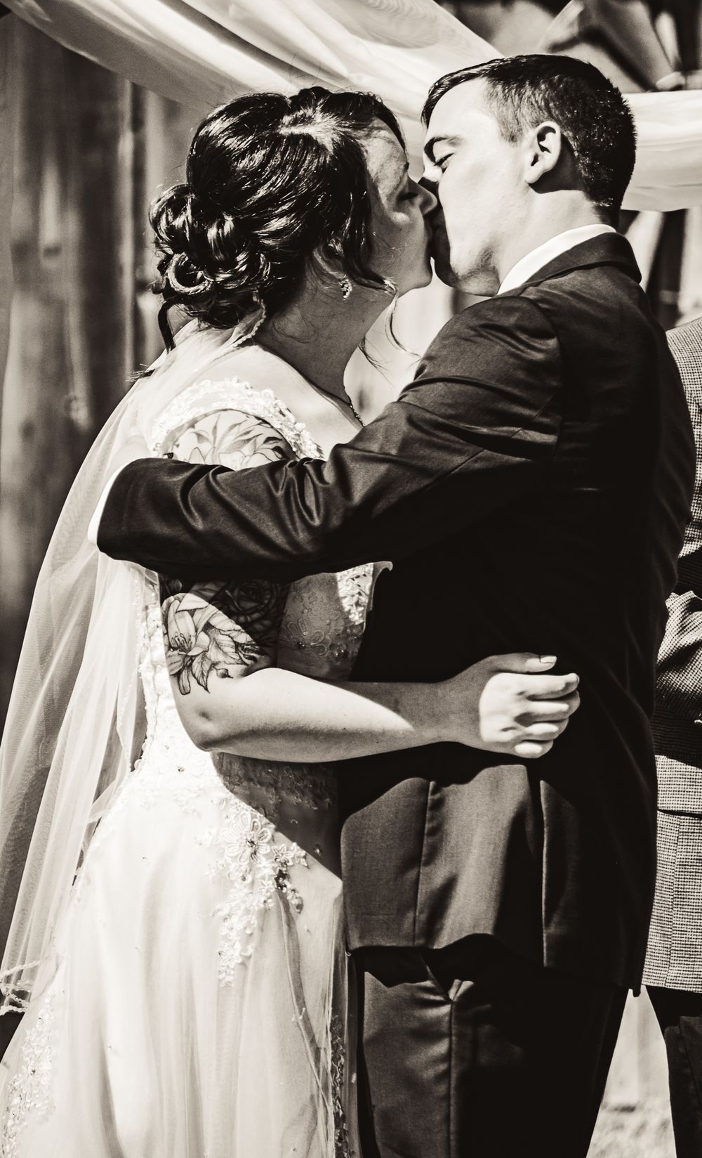 Black and white photo capturing an intimate wedding kiss moment.