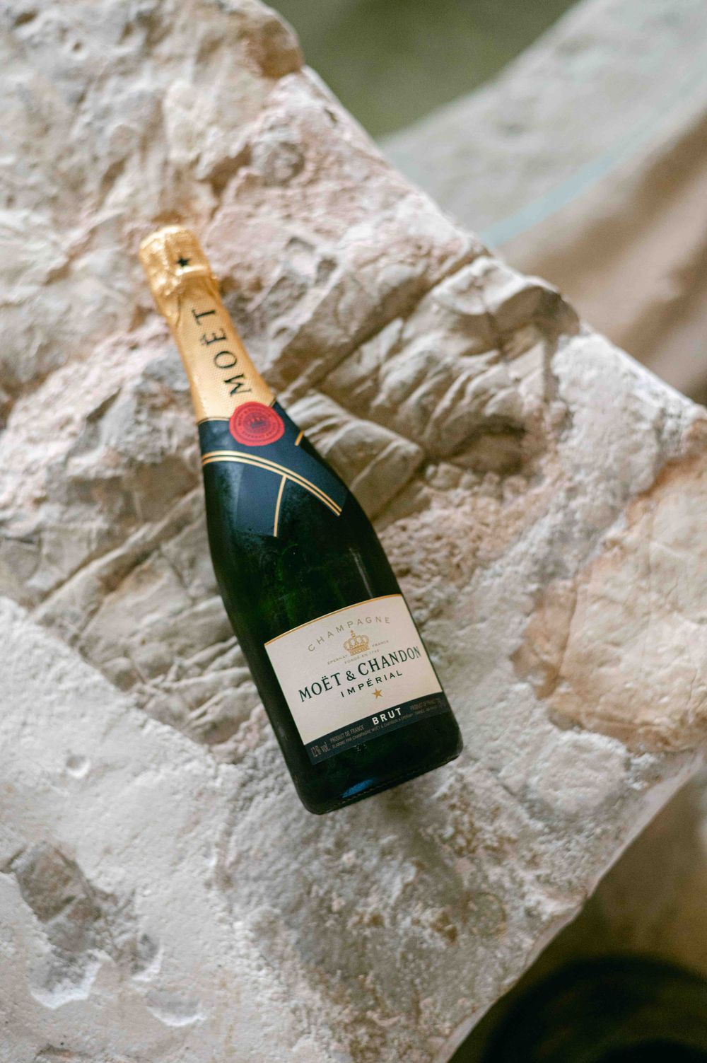 Moet & Chandon champagne bottle resting on white limestone surface.