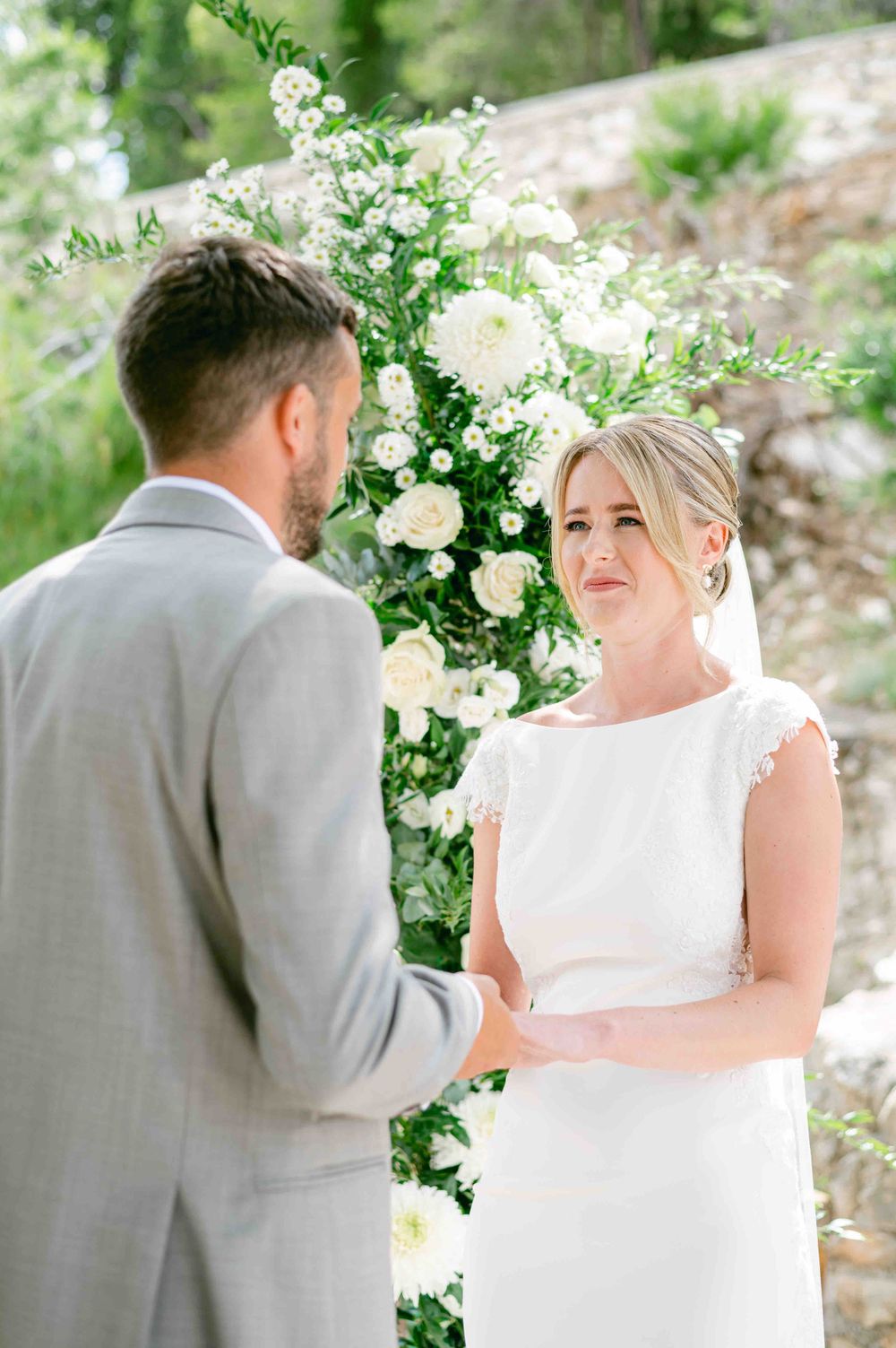 Intimate wedding ceremony moment with couple exchanging vows under white floral arrangements.