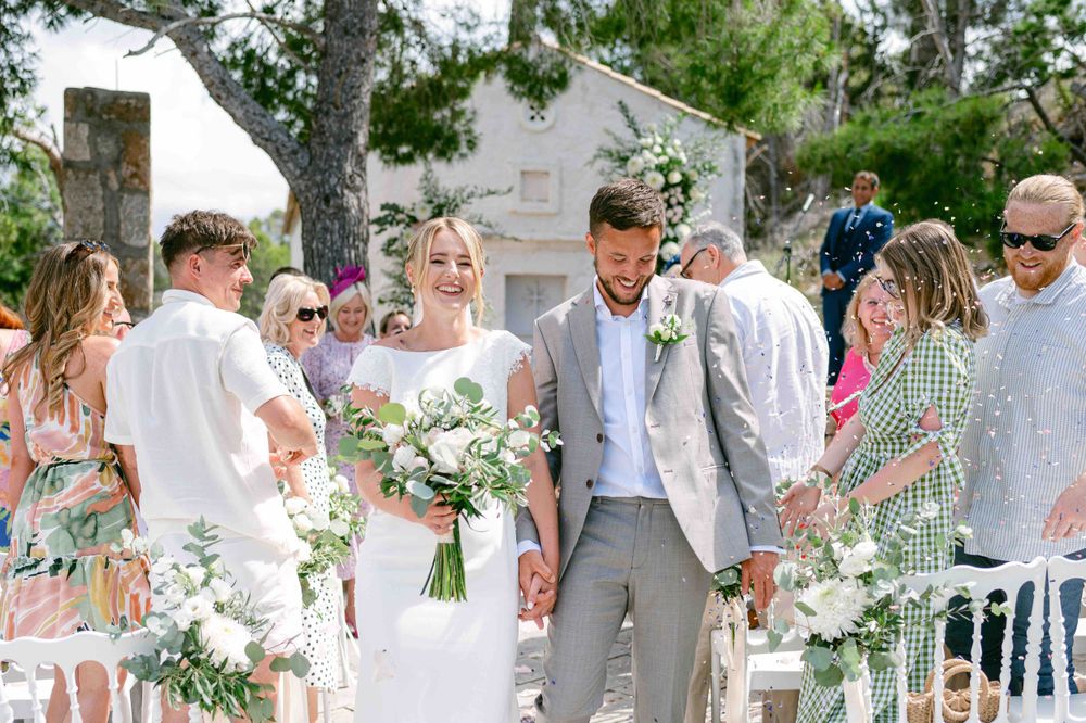 Wedding guests congratulating couple during outdoor ceremony recessional.