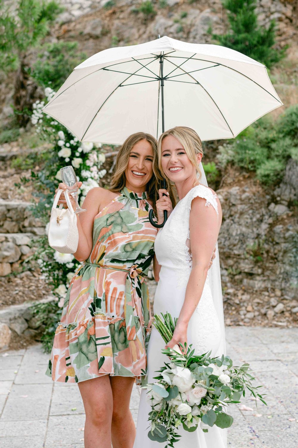 Celebratory moment under white umbrella with floral decor in background.