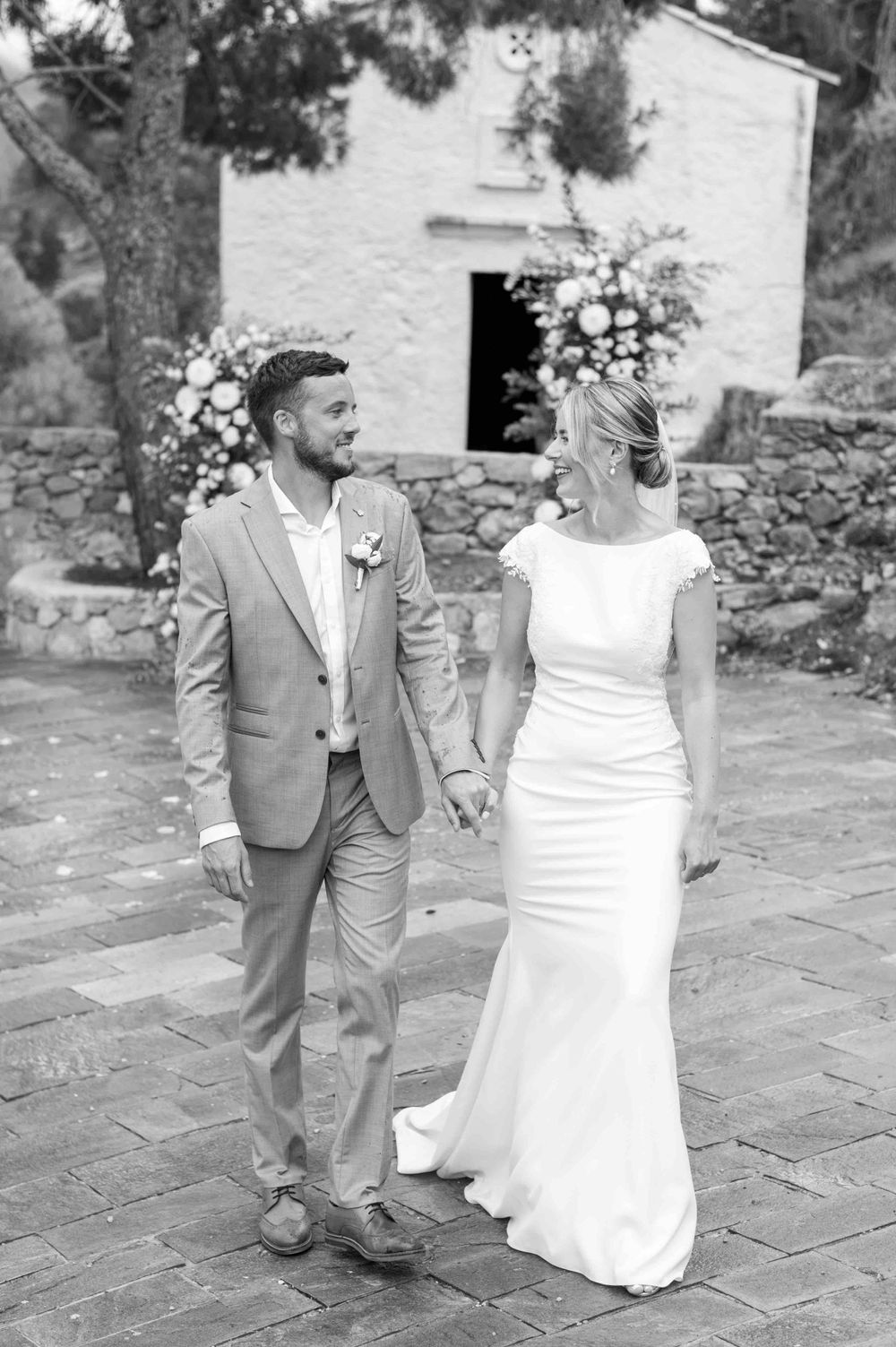 Black and white wedding portrait with couple walking on stone pathway.