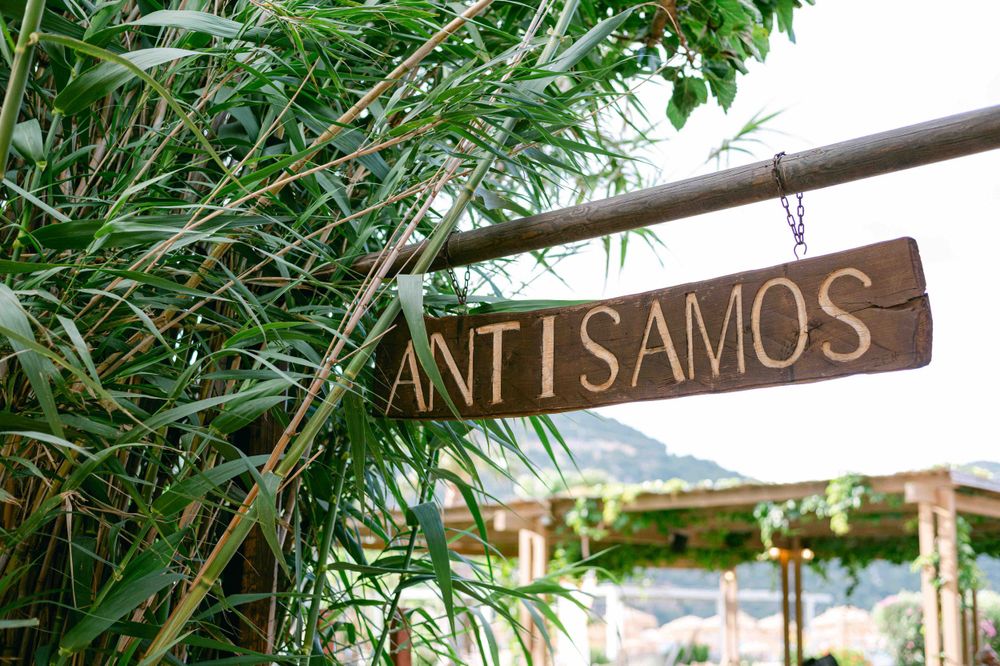 Wooden Antisamos sign surrounded by lush greenery.