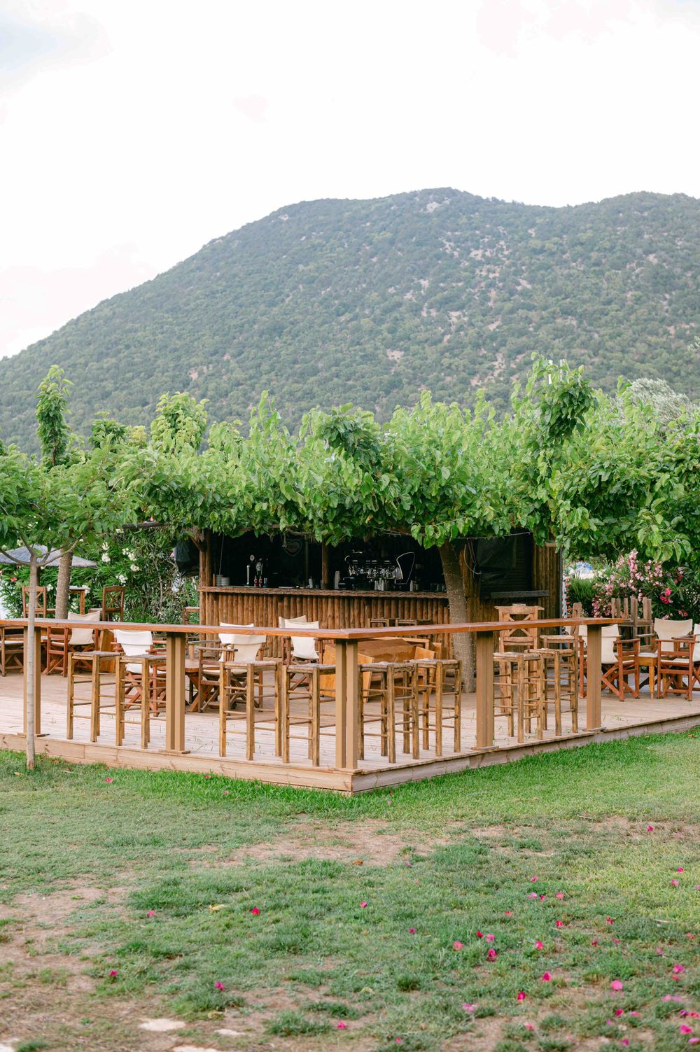Outdoor dining area with wooden furniture set against mountain backdrop.
