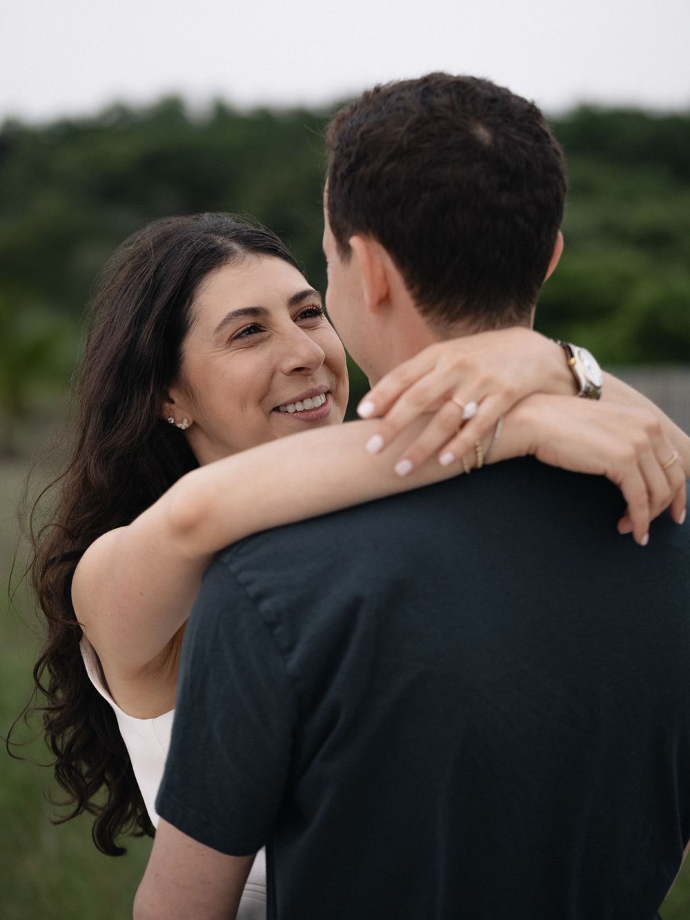 A tender embrace captured between two people during a beach engagement session.