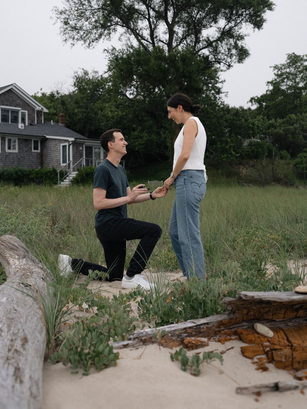 A beachside proposal scene with a couple against the backdrop of a coastal house.