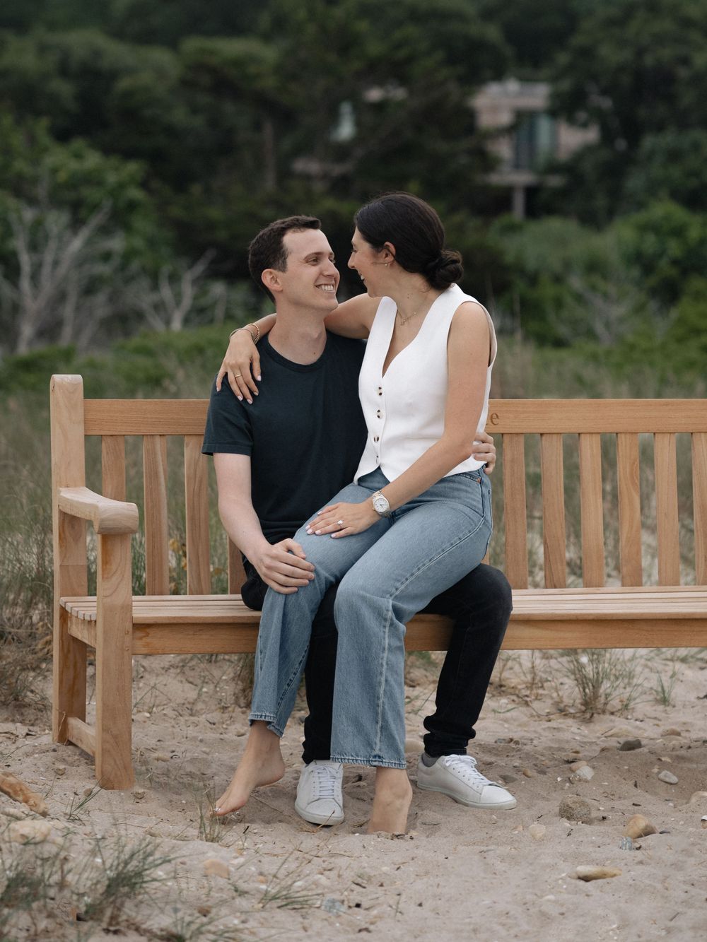 Couple sharing a romantic moment on wooden bench at sandy beach location.