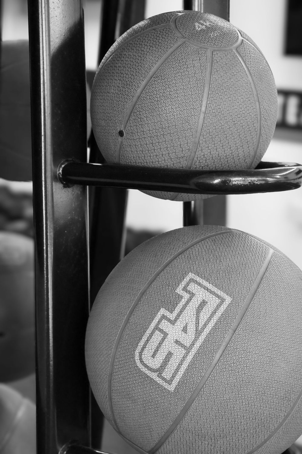 Black and white close-up of medicine balls on a rack branded with F45 Training logo in a gym.