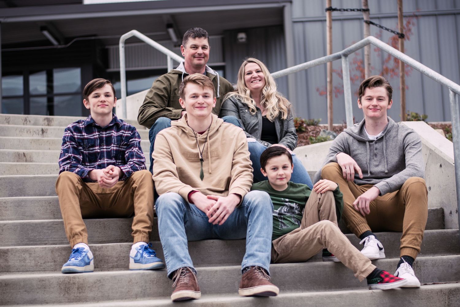 Group of people sitting casually on concrete steps outside a building.