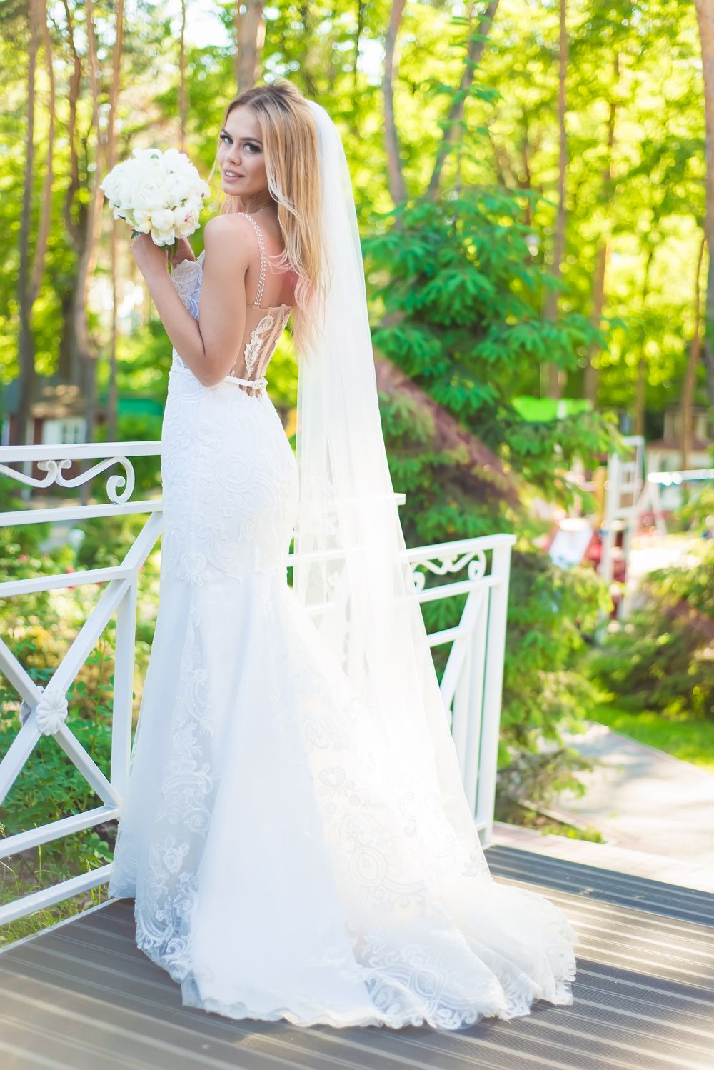Bridal portrait series on white garden gazebo in natural sunlight.