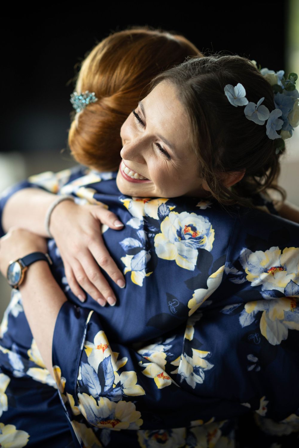 bride hugs sister in floral dressing gown during bridal preparations at the elvetham hotel