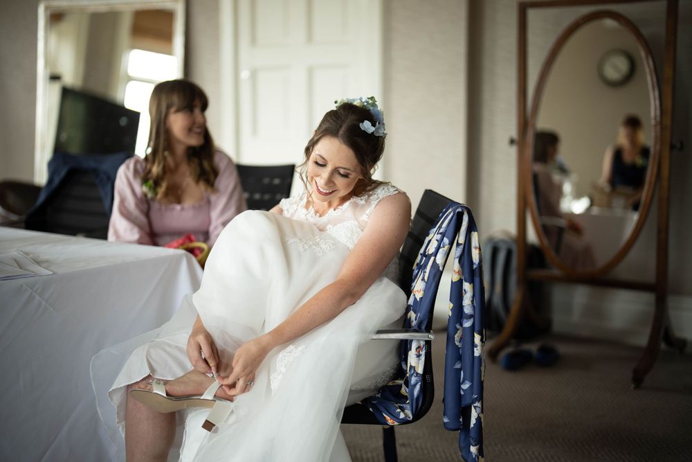 bride puts on her shoes at the elvetham hotel