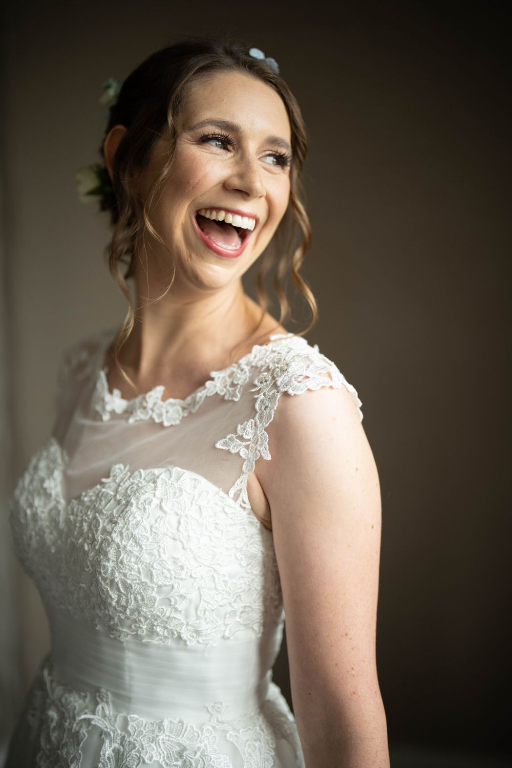 laughing bride looks out at the gardens from her suite window