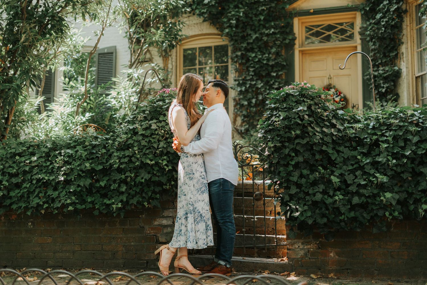 A romantic embrace in front of an ivy-covered building on a sunny day.