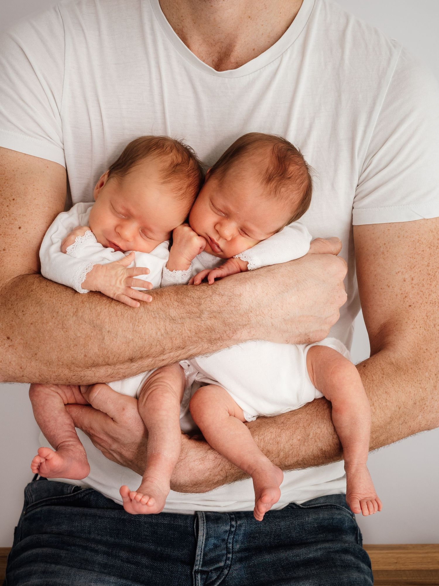 Newborn twin babies held in fathers arms, taken in Didcot by Verity Photography