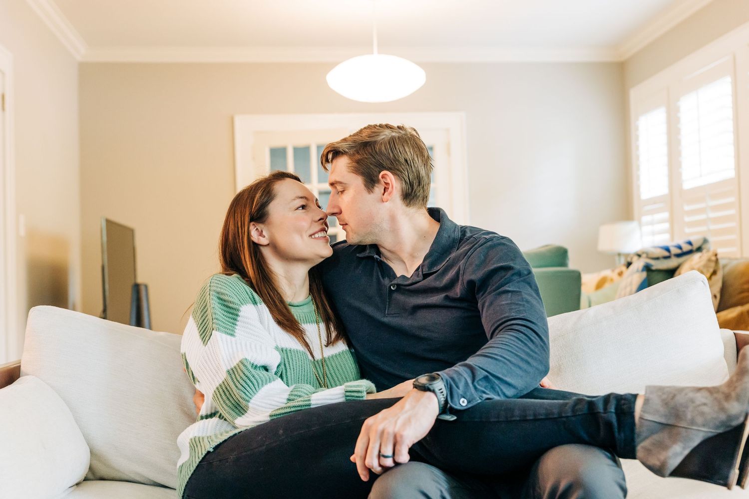 A mom and dad snuggling on the couch together