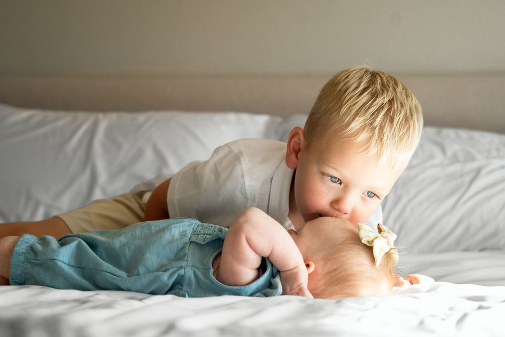 in home portrait session San Antonio Texas toddler boy kisses newborn baby sister on head
