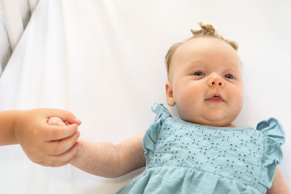 in home portrait session San Antonio Texas newborn baby girl laying in crib toddler brother holding her hand