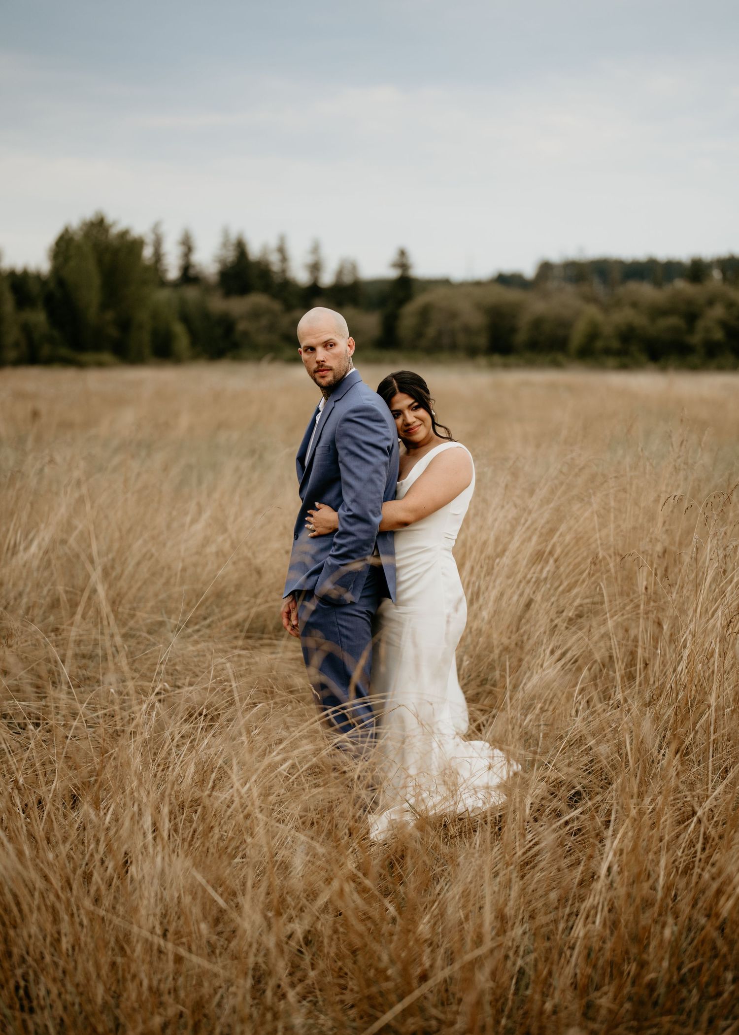 Bride and Groom standing in wheat field posing in their wedding outfits in Seattle WA