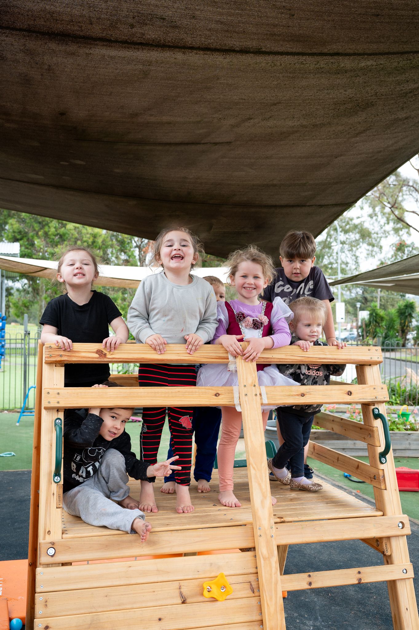 group of preschool kids playing on a wooden structure