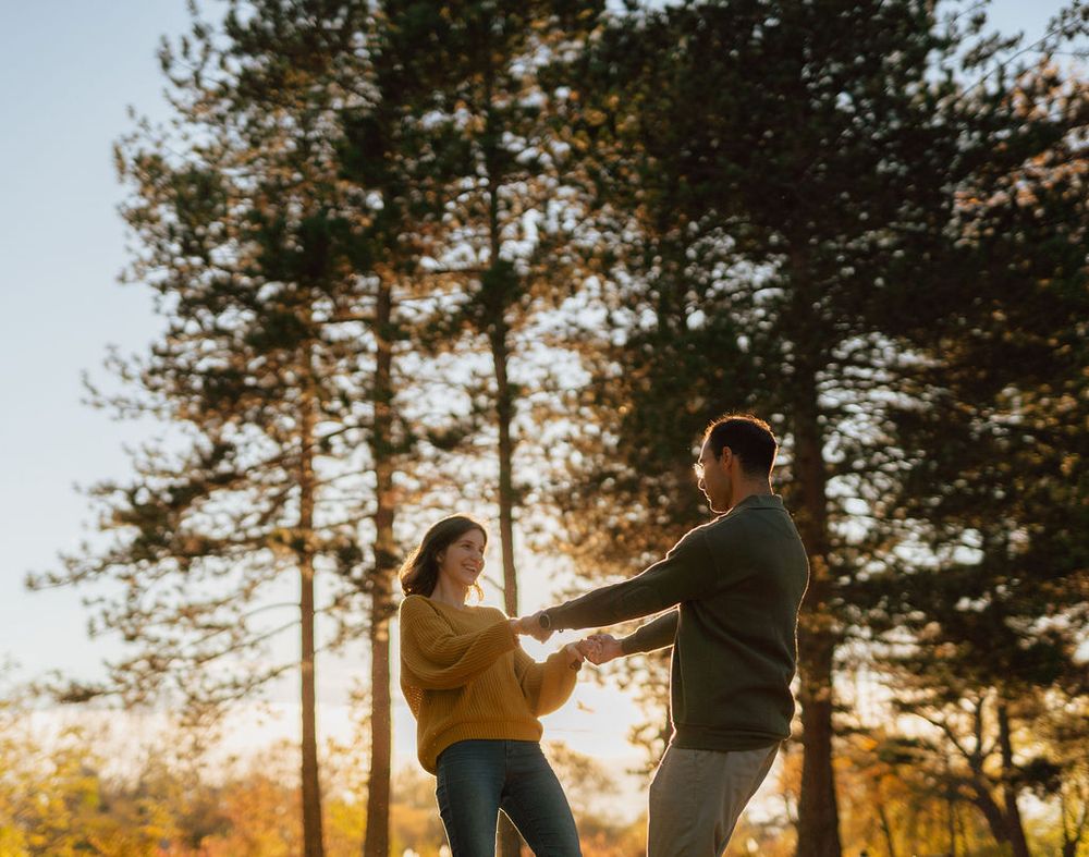 Couple dancing in golden sunlight with pine trees in background.